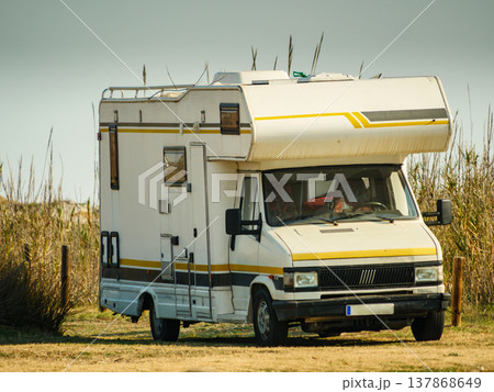 Camper parked in an open field during daylight hours near a beach dunes with tall grasses Camper parked in an open field during daylight hours near a beach dunes with tall grasses 137868649
