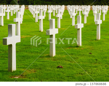 Graves with white crosses arranged in rows on green grass in a memorial cemetery during daylight hours Graves with white crosses arranged in rows on green grass in a memorial cemetery during daylight hours 137868686