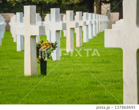 Crosses stand in a row as flowers sit at a grave in a cemetery where people remember their loved ones 137868695