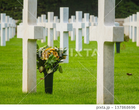 Crosses stand in a row as flowers sit at a grave in a cemetery where people remember their loved ones 137868696