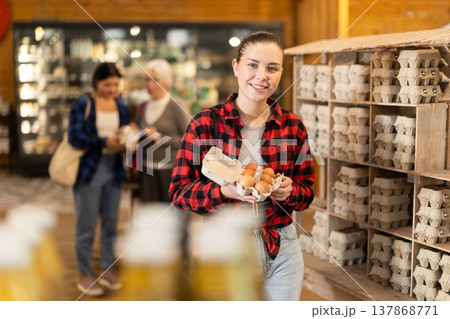 Girl selects and buys chicken eggs at grocery supermarket. Girl selects and buys chicken eggs at grocery supermarket. 137868771