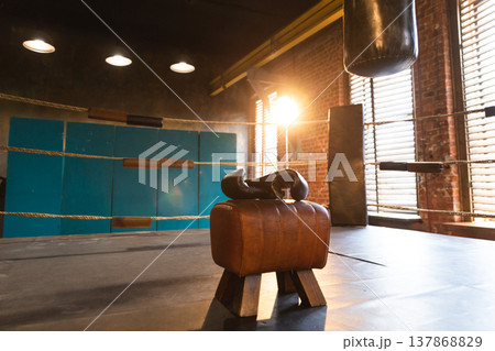 Boxing gloves lying down on boxing ring in empty gym. Equipment for fight training competition black protective boxing gloves ready for fighter winner on ring. Strength fit body workout training 137868829