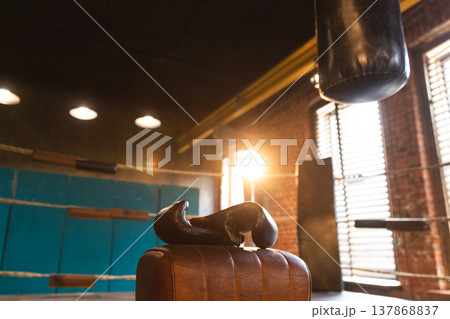 Boxing gloves lying down on boxing ring in empty gym. Equipment for fight training competition black protective boxing gloves ready for fighter winner on ring. Strength fit body workout training 137868837