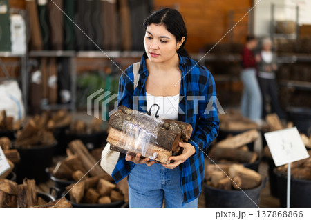 Young woman choosing firewood in store Young woman choosing firewood in store 137868866