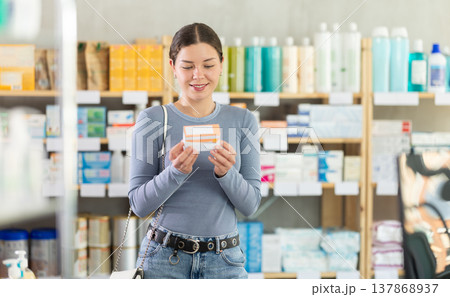 Young girl customer choosing pills in box in drugstore Young girl customer choosing pills in box in drugstore 137868937