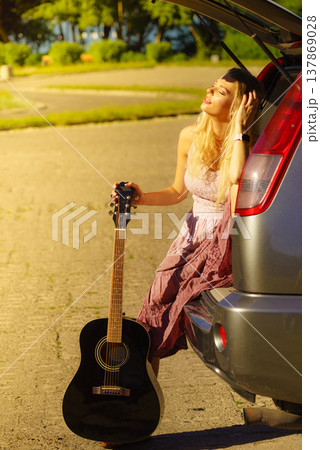 Girl with guitar on hatchback car 137869028
