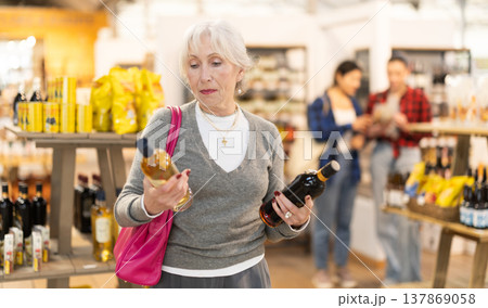 Elderly woman chooses wine at grocery store 137869058