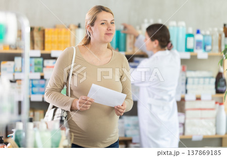 Pregnant woman chooses prescription pills at pharmacy Pregnant woman chooses prescription pills at pharmacy 137869185