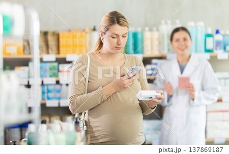 Pregnant woman using phone to verify supplement safety 137869187