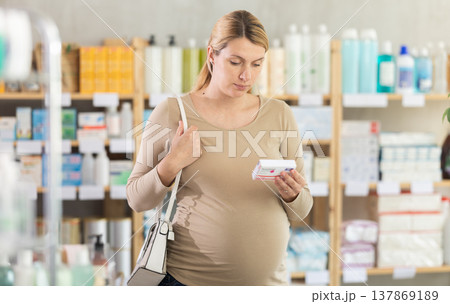 Pregnant woman chooses pills at pharmacy Pregnant woman chooses pills at pharmacy 137869189