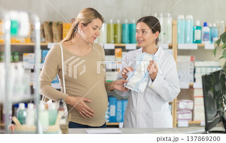 Pharmacist helping pregnant woman to choose baby diapers in pharmacy Pharmacist helping pregnant woman to choose baby diapers in pharmacy 137869200