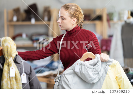 While shopping, teen girl browsing goods items and choose elect something warm outerwear in store While shopping, teen girl browsing goods items and choose elect something warm outerwear in store 137869239