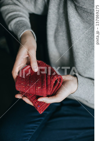 Female hands with red hand knitted socks. 137869275