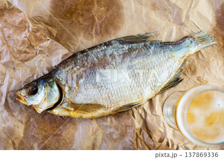 On table covered with paper is beer and snack - dried jerked bream, whole fish On table covered with paper is beer and snack - dried jerked bream, whole fish 137869336