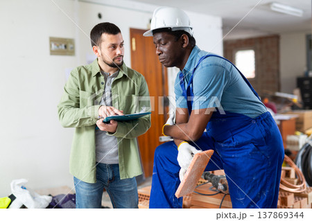 Engineer shows the estimate to a builder, explaining the working moments 137869344