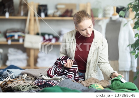 Selective teen girl choosing sweater in clothing store Selective teen girl choosing sweater in clothing store 137869349