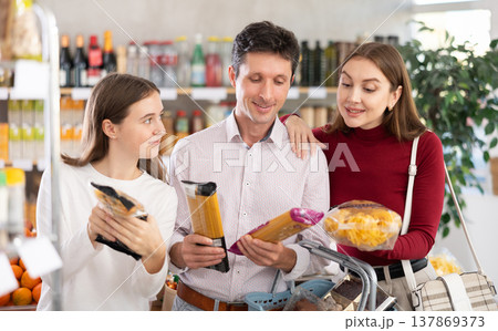 Couple man and woman with girl choosing pasta in grocery 137869373