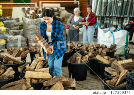 Young woman choosing firewood in store 137869374