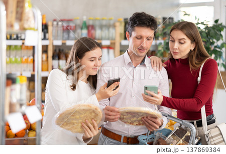 Family with teenage girl scanning QR on bottle of smoothie in supermarket Family with teenage girl scanning QR on bottle of smoothie in supermarket 137869384
