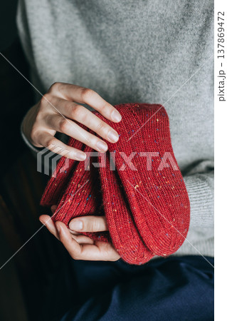 Female hands with red hand knitted socks. 137869472
