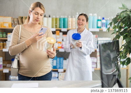 Pregnant woman buyer scans baby formula qr code with woman pharmacist 137869515