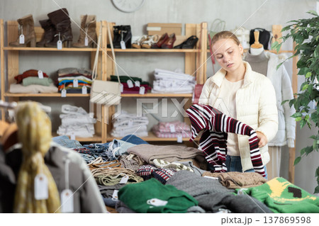 While shopping, teen girl browsing goods items and choose elect warm jumper in store While shopping, teen girl browsing goods items and choose elect warm jumper in store 137869598