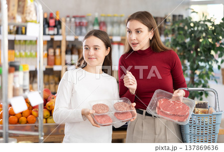 Teenage girl and her mother choosing hamburger or beef entrecote in grocery Teenage girl and her mother choosing hamburger or beef entrecote in grocery 137869636