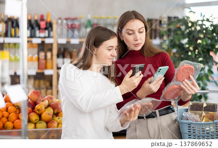 Mom and daughter scanning packages of hamburger patties Mom and daughter scanning packages of hamburger patties 137869652