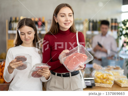 Woman and her teenage daughter choosing hamburger or beef entrecote in grocery Woman and her teenage daughter choosing hamburger or beef entrecote in grocery 137869663