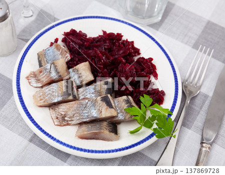 Slightly salted herring slices with grated beets and greens 137869728