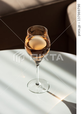 Rose Wine Glass with Shadows on White Table. Elegant Minimalist Scene 137869790