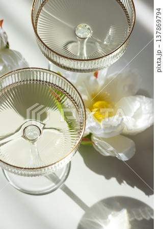 Champagne Glasses with Flowers under Sunlight. Elegant Celebration Scene 137869794