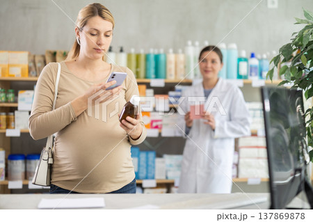 Pregnant woman scanning syrup bottle with phone to check ingredients online 137869878