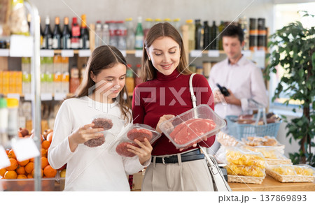 Woman with daughter chooses hamburger or entrecote Woman with daughter chooses hamburger or entrecote 137869893