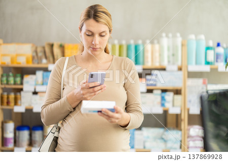 Pregnant woman customer scanning QR-code on ointment box Pregnant woman customer scanning QR-code on ointment box 137869928