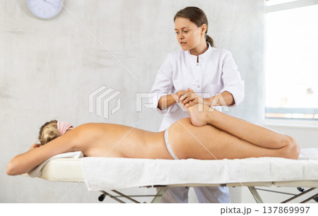Young woman masseuse doing foot massage 137869997