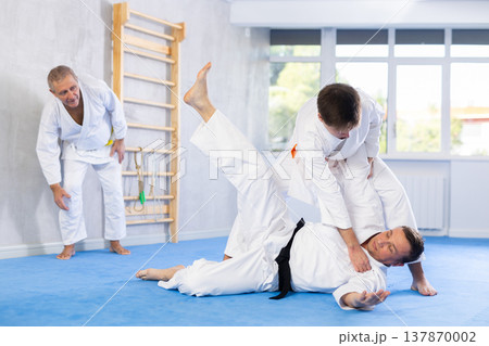 Young guy working on martial arts skills in training fight with male rival Young guy working on martial arts skills in training fight with male rival 137870002