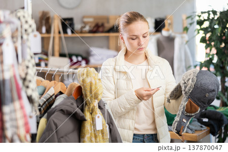 While shopping, teen girl browsing goods items and choose elect fur hat in store While shopping, teen girl browsing goods items and choose elect fur hat in store 137870047