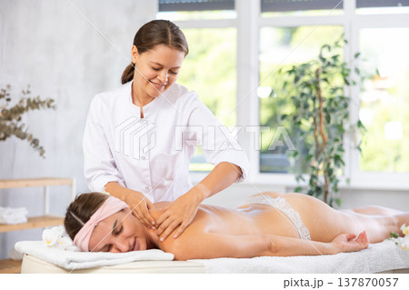 Young woman masseuse doing back massage 137870057