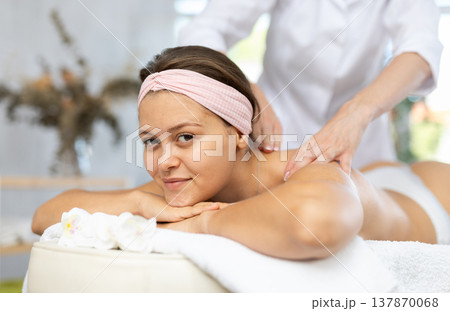 Female masseur works out shoulder and back problem area for female athlete client. Close-up 137870068