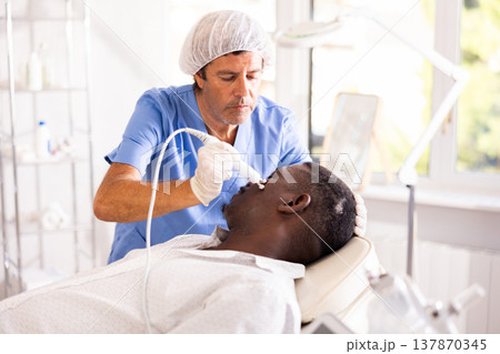 Doctor uses RF-lifting beauty machine nozzle for stimulate collagen production 137870345