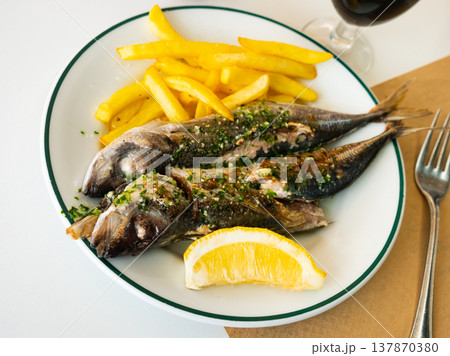 Grilled mackerels with French fries, lemon and sauce 137870380