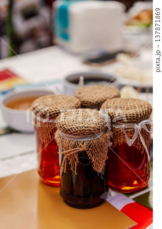 Vivid Imagery Of Homemade Preserves Displayed On Country Style Marketplace Table With Warm Ambiance Vivid Imagery Of Homemade Preserves Displayed On Country Style Marketplace Table With Warm Ambiance 137871869