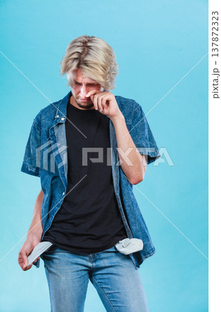 Upset sad man showing empty pockets 137872323