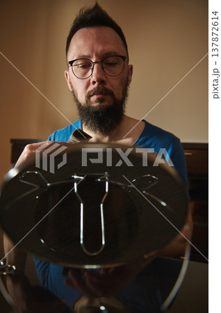 Man Trimming Beard With Electric Trimmer While Looking Into Mirror At Home 137872614