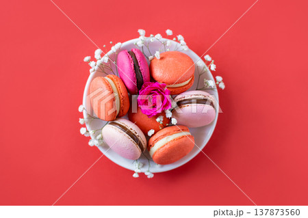 Tasty french macarons with flowers on a red background. 137873560