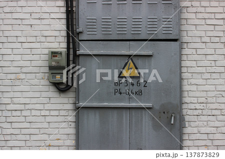 Power Sign On A Steel Gate In Concrete Bricks Wall Of Electric Booth With Outdoor Switch And High Voltage Cable Power Sign On A Steel Gate In Concrete Bricks Wall Of Electric Booth With Outdoor Switch And High Voltage Cable 137873829