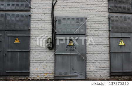 Three Grey Metal Doors With High Voltage Signs On A White Brick Wall Texture Background Three Grey Metal Doors With High Voltage Signs On A White Brick Wall Texture Background 137873830