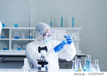 Scientist man look into Microscope research in science laboratory. Asian scientist look at microbiology microscope laboratory equipment chemistry lab. Biochemistry research experiment vaccine concept 137874477
