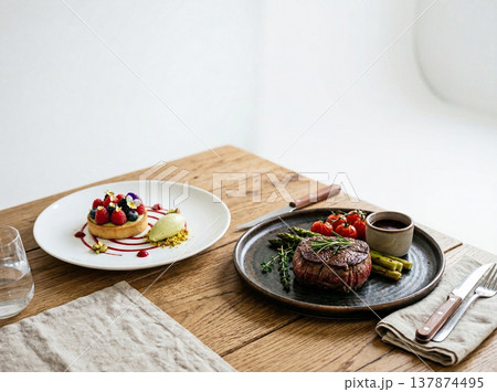 Elegant dinner setting with seared steak, asparagus, cherry tomatoes, and fruit tart dessert, fine dining experience, food photography 137874495